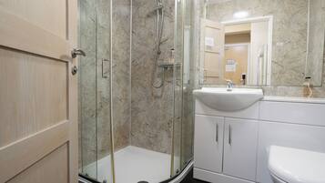Un bagno moderno con doccia vetrata, un lavandino bianco e uno specchio grande.