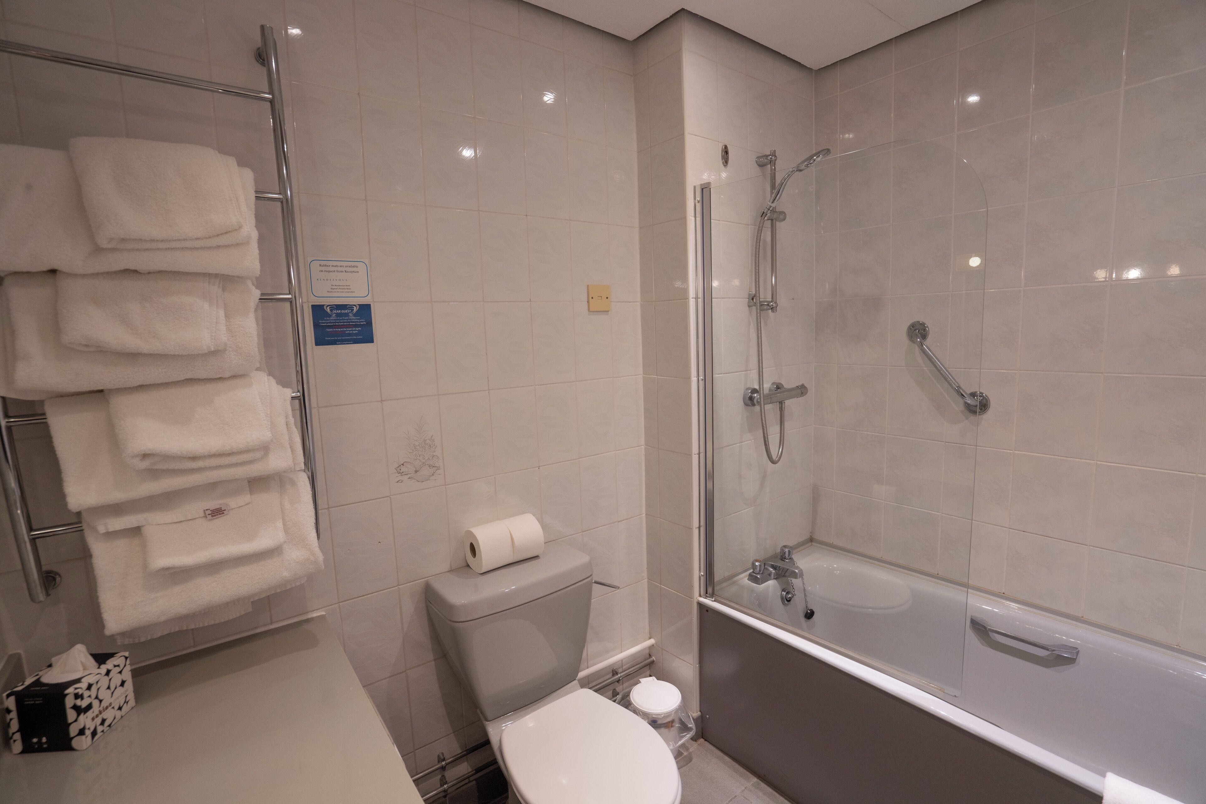 Une salle de bain comprenant des toilettes, une pile de serviettes blanches, une cabine de douche en verre et une baignoire.