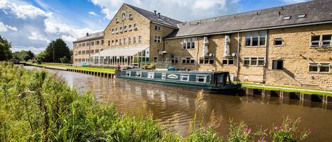 Un bâtiment situé au bord d’un canal, avec un bateau vert amarré devant.