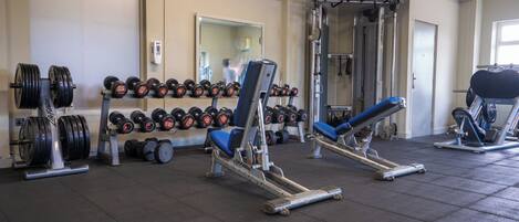 A gym with weightlifting equipment, dumbbells, and exercise machines.