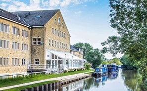 A riverside building with multiple windows and a covered walkway.
