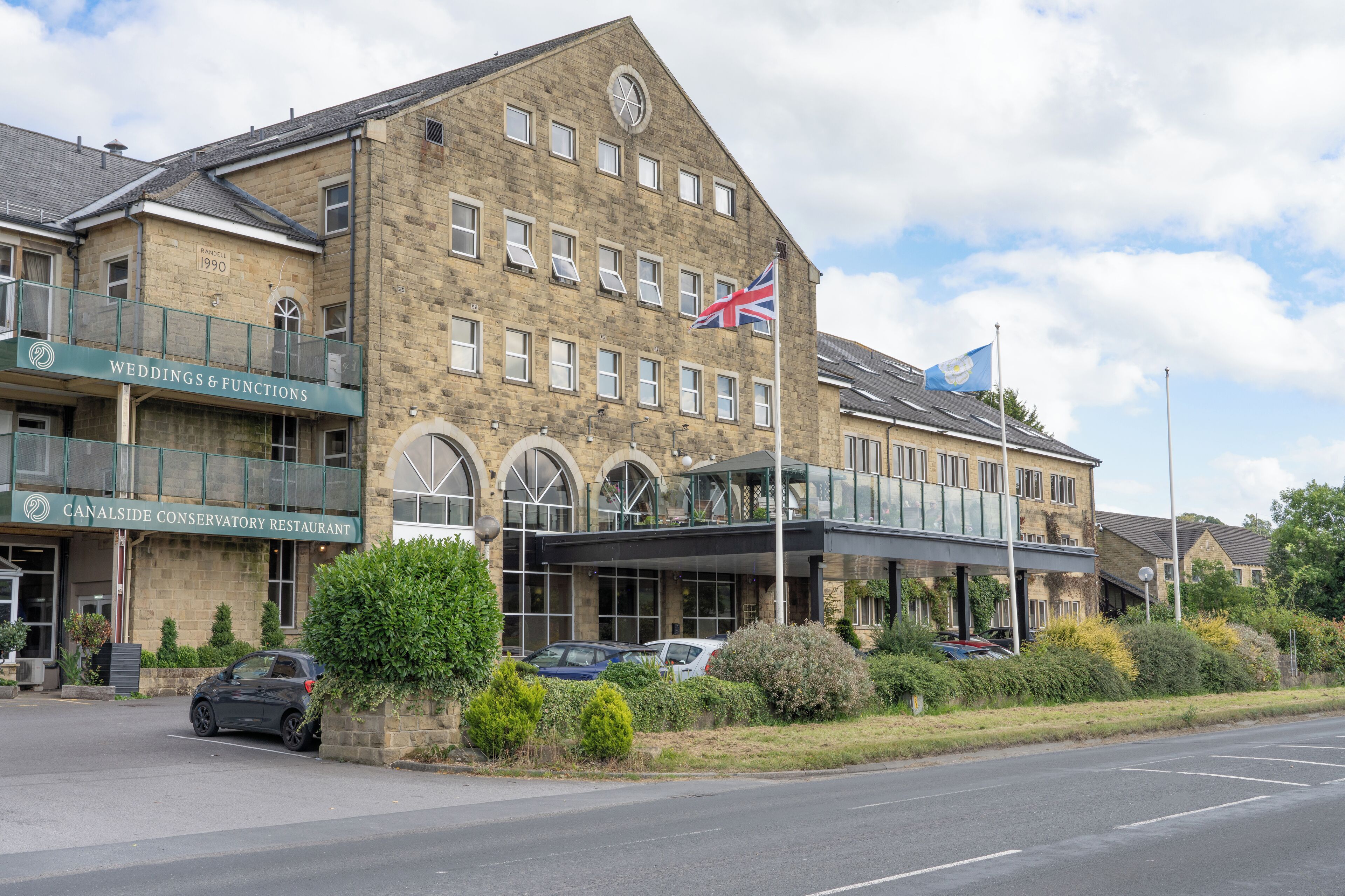 A historic building with a sign for weddings and functions, a conservatory restaurant, and a flag.