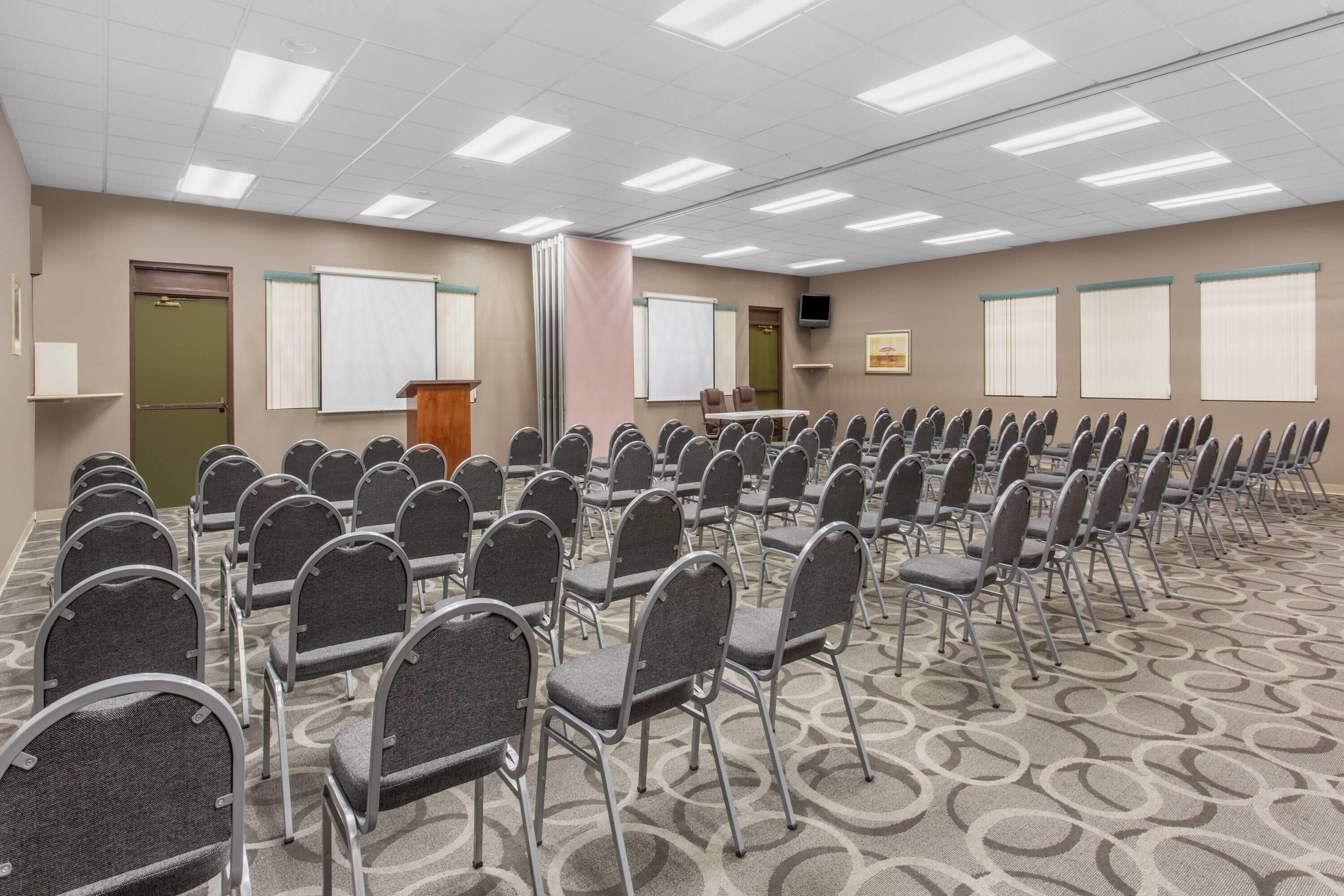 Ein Konferenzraum mit Reihen von Stühlen, einem Rednerpult und Whiteboards an den Wänden.