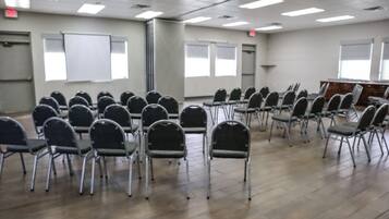 Un salón de conferencias con filas de sillas, un atril y una pizarra.