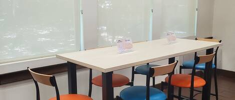 Ein Konferenzraum mit einem weißen Tisch und vier Stühlen, jeweils mit einem Kissen in unterschiedlicher Farbe.