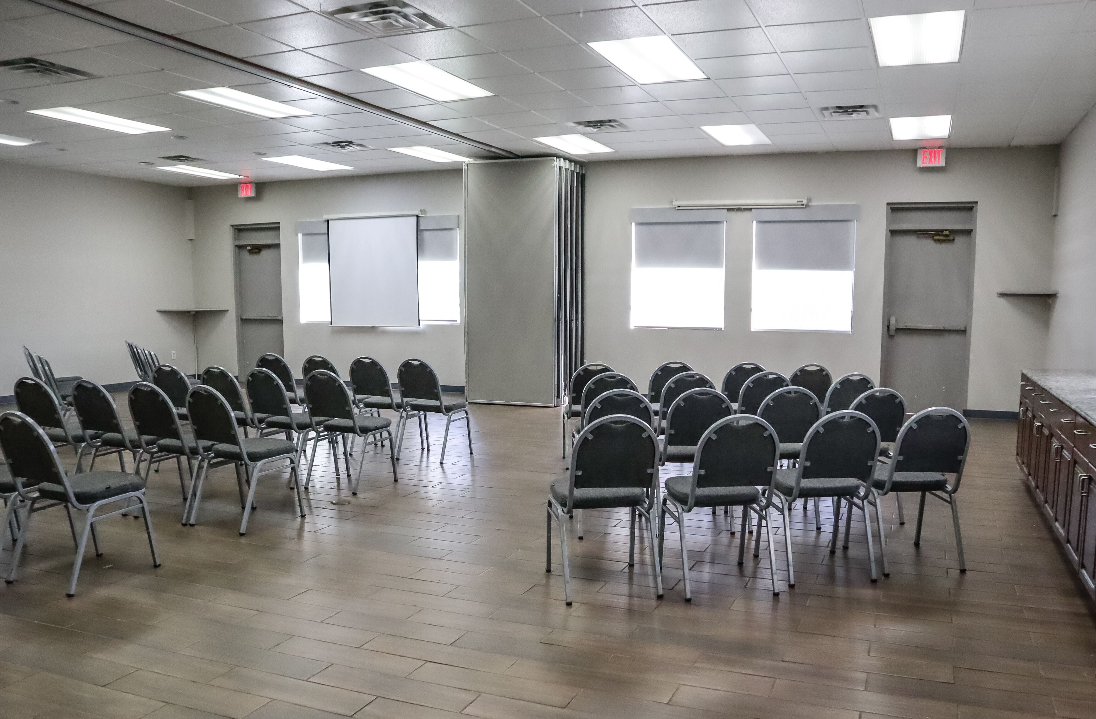 A conference room with rows of chairs, a whiteboard, and windows.