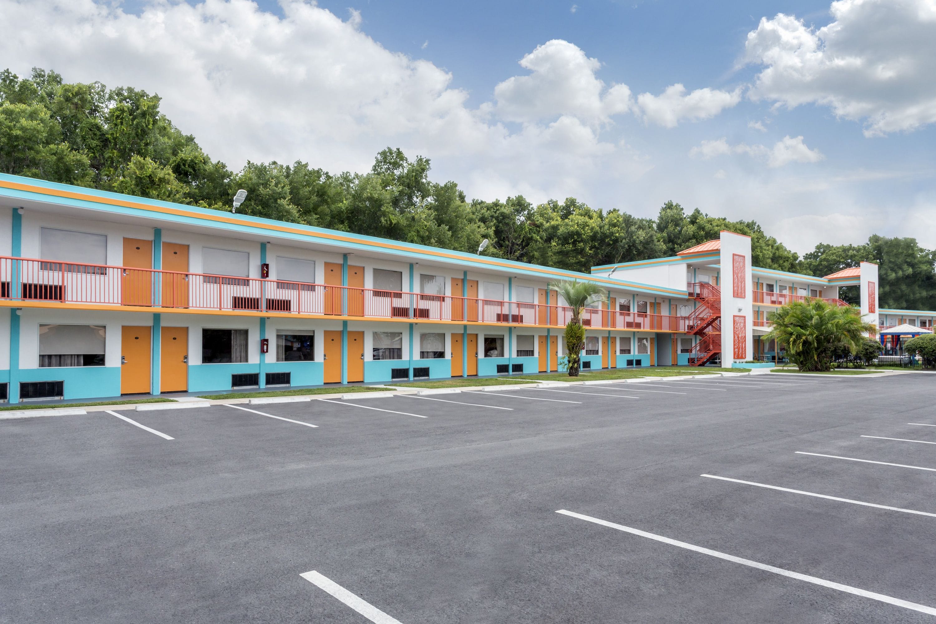 A motel with multiple rooms, a parking lot, and a red staircase.