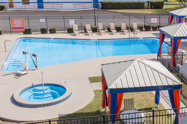 Une piscine avec des chaises longues et un petit espace équipé d’un jacuzzi.