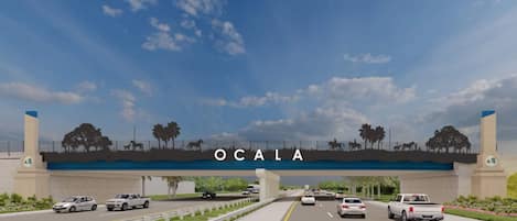 A highway overpass with the word "OCALA" and silhouettes of horses and trees.