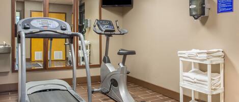 A fitness center with a treadmill, an elliptical, a TV, and a towel rack.