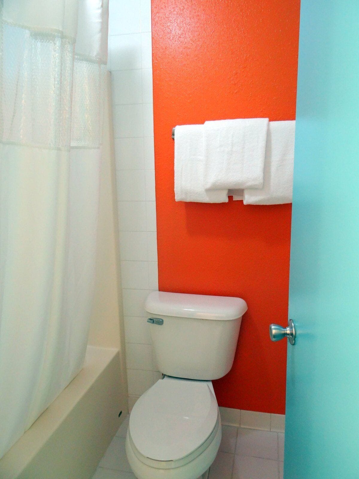 Un baño con inodoro blanco, cortina de ducha y un toallero con dos toallas blancas.