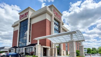 Hotel entrance with covered walkway and parking area.