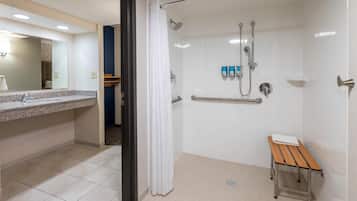 A modern bathroom with a shower, a sink, and a bench.