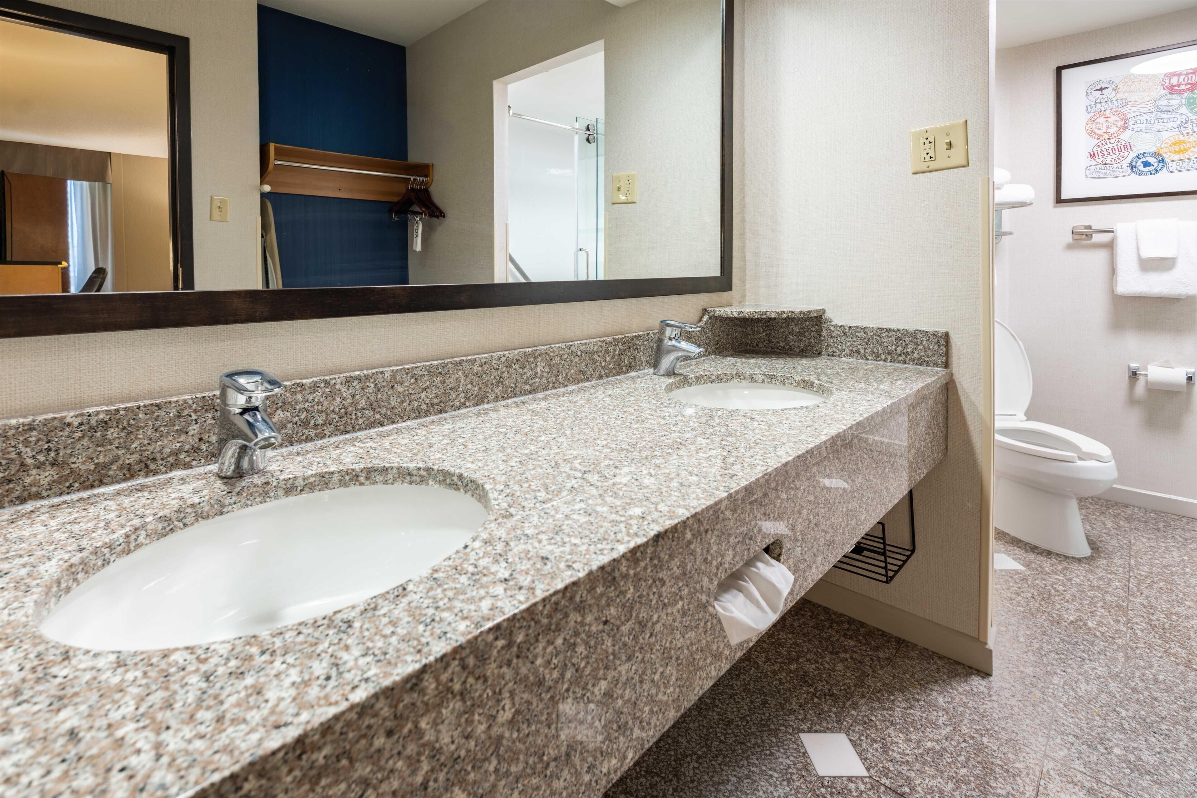 A bathroom with two sinks, a large mirror, and a toilet.