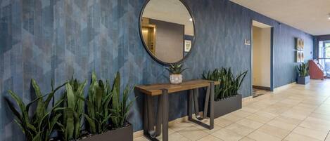 A reception area with a wooden console table, a large mirror, and potted plants.