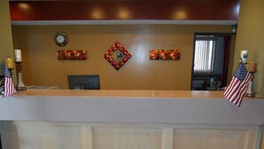 A reception desk with a clock, decorative wall art, and American flags.