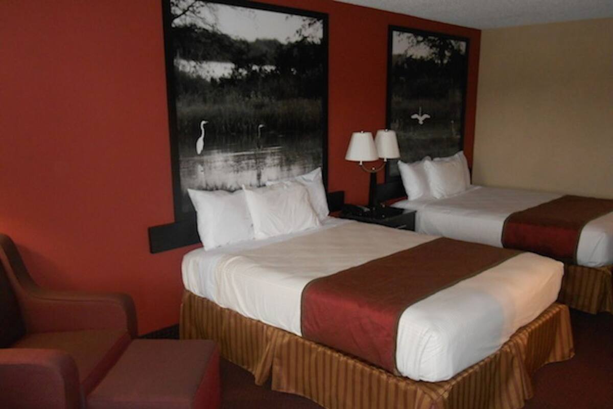 A hotel room with two beds, a desk, and a chair.