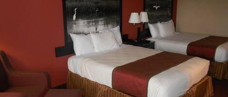 A hotel room with two beds, a desk, and a chair.