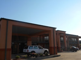 A building with a covered entrance and a white SUV parked in front.