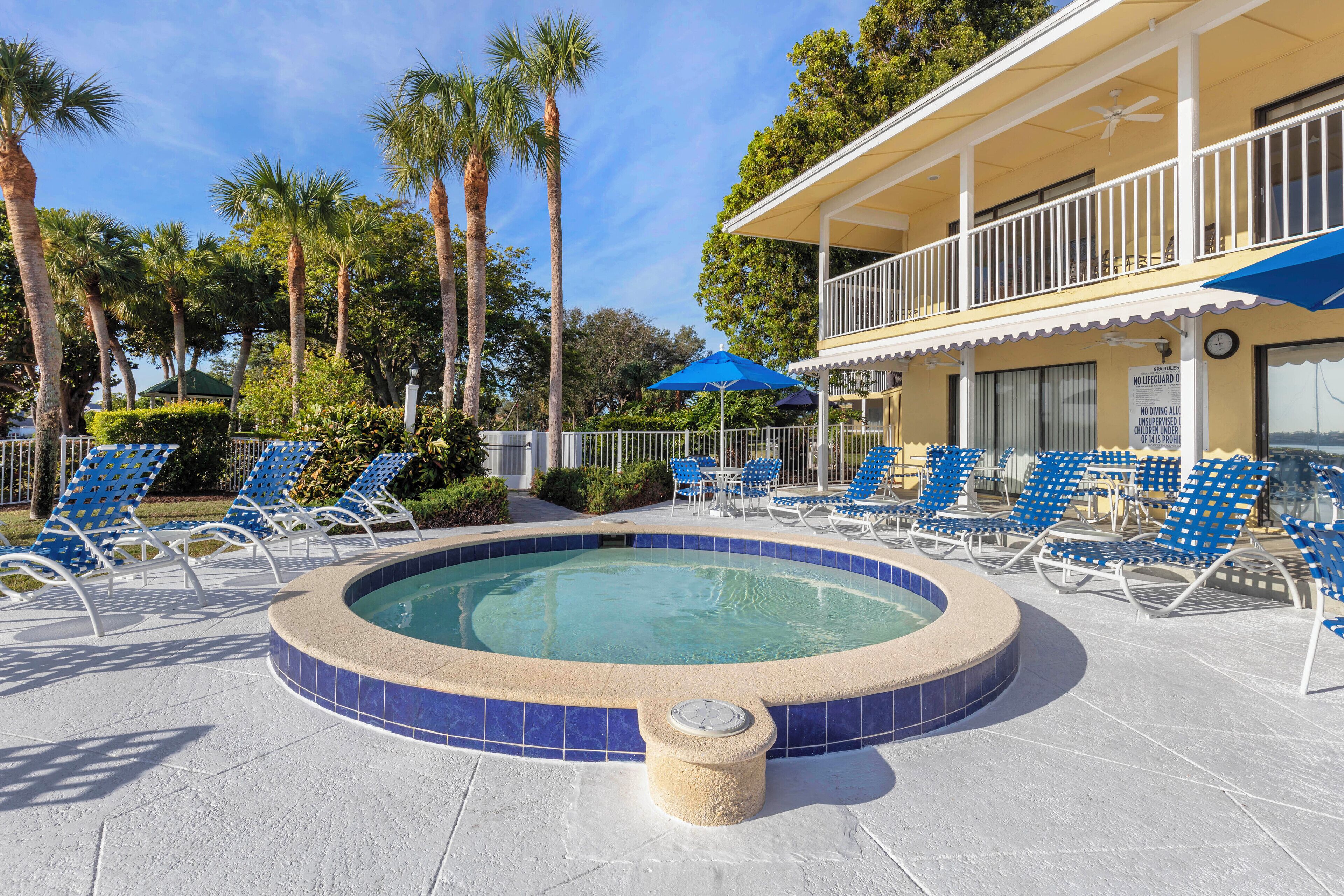 A pool area with lounge chairs and a hot tub.