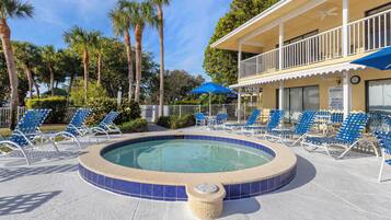 A pool area with lounge chairs and a hot tub.