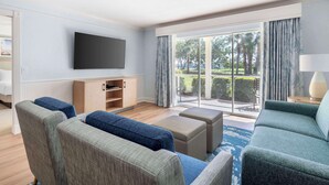 A modern living room with a flat-screen TV, a wooden cabinet, and a large sliding glass door leading to a balcony. - Hilton Vacation Club Charter Club Naples Bay (Naples)
