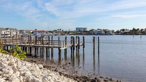 A marina with docked boats, a wooden pier, and buildings in the background. - Hilton Vacation Club Charter Club Naples Bay (Naples)