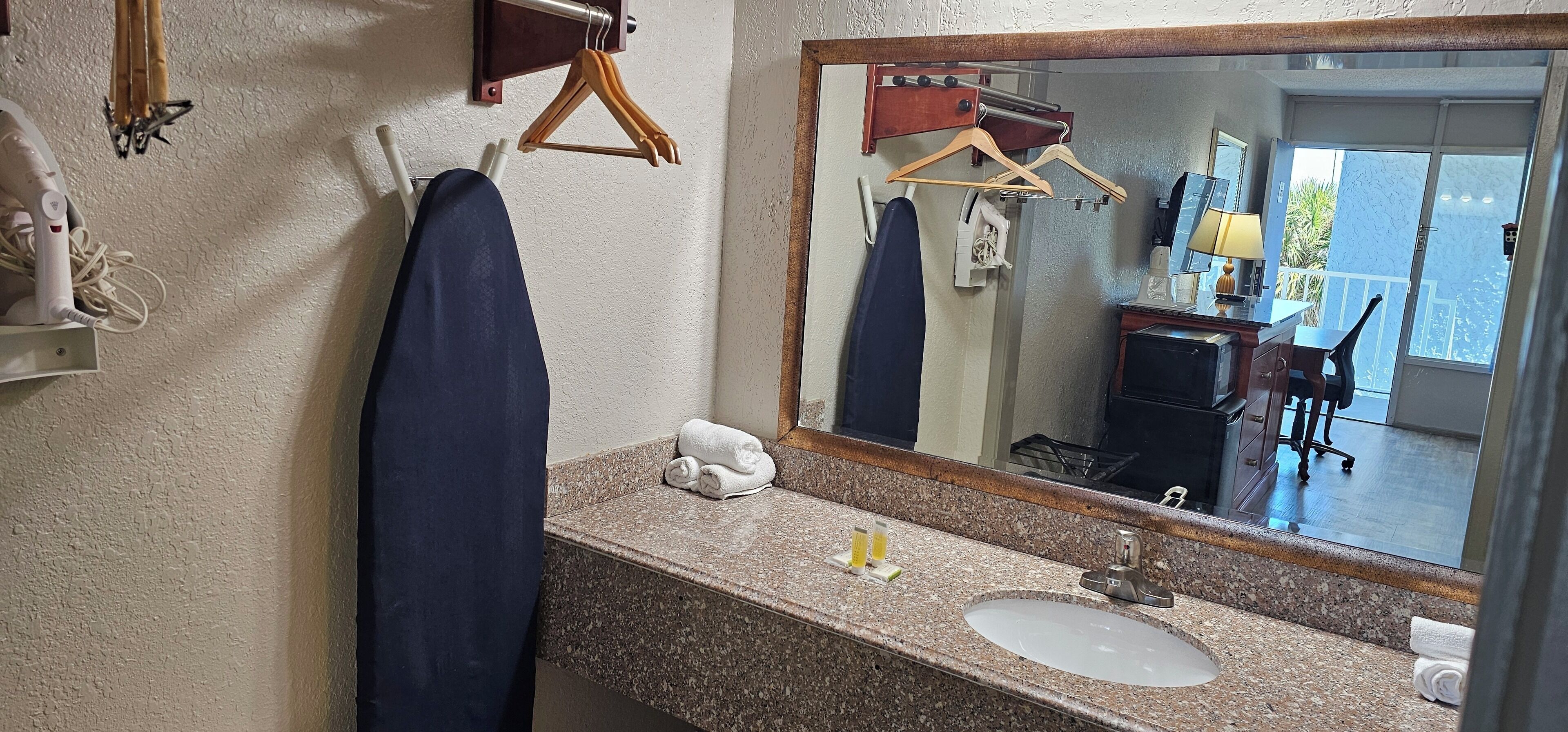 Une salle de bain avec un comptoir en granit, un lavabo, un miroir et un porte-serviettes.