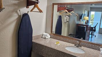 Une salle de bain avec un comptoir en granit, un lavabo, un miroir et un porte-serviettes.