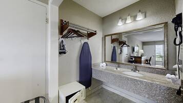 A bathroom with a large mirror, two sinks, a shower, and a hairdryer mounted on the wall.