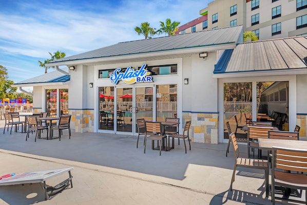 An outdoor seating area with tables and chairs at a bar named 'Splash Bar.'