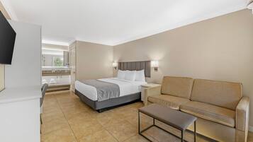 A hotel room with a bed, a sofa, a small table, and a TV.