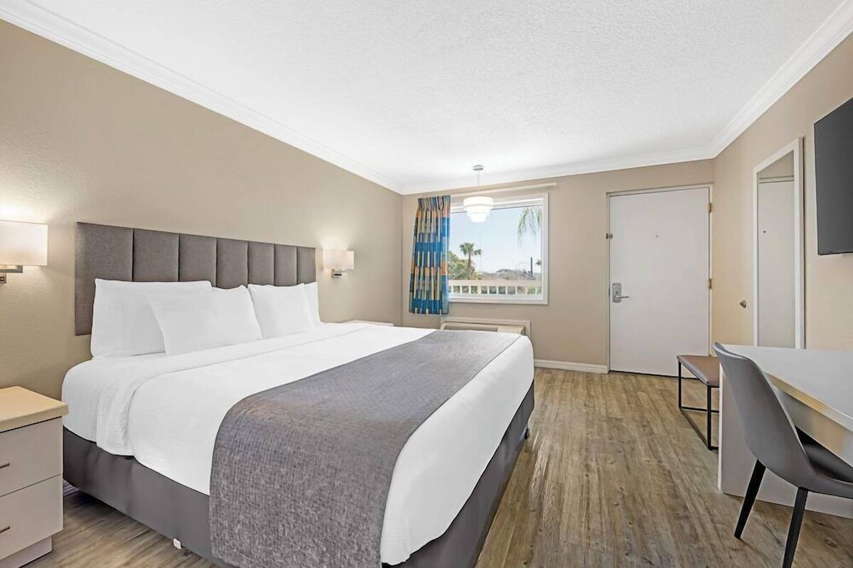 Ein Hotelzimmer mit Bett, Nachttischen, Schreibtisch und Stuhl.