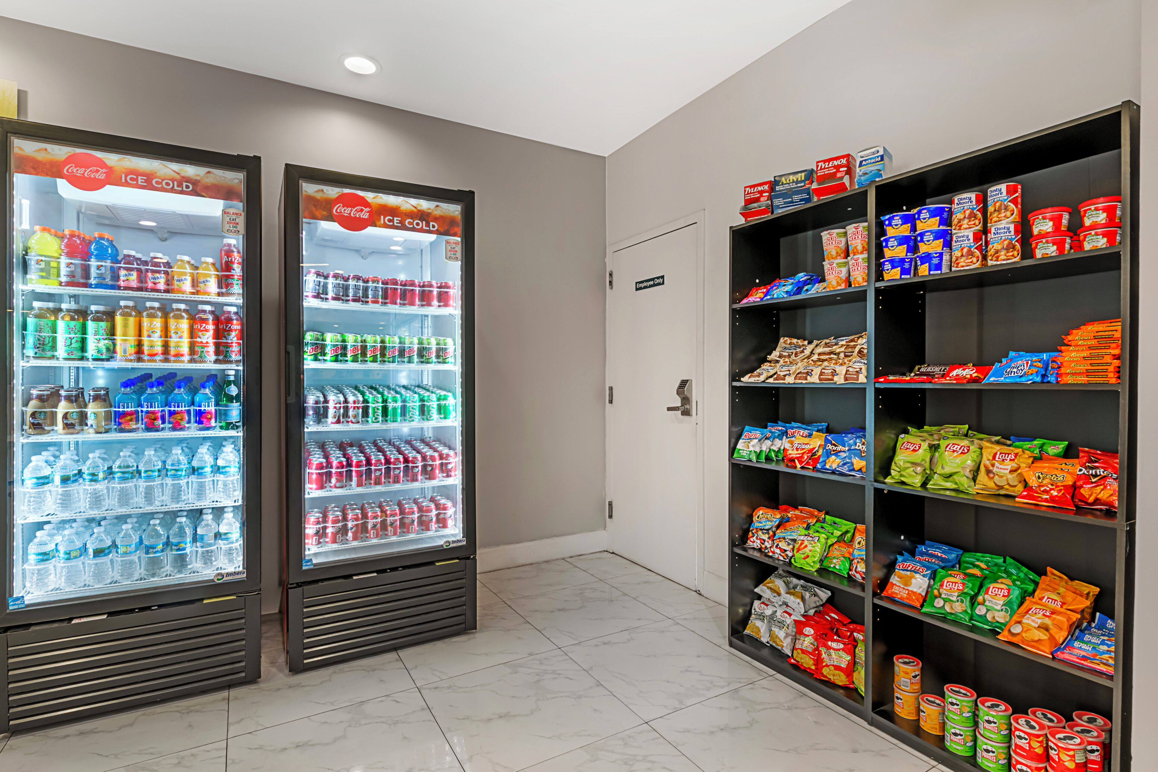 Two ice cold beverage dispensers, a snack shelf, and a door marked 'Employee Only'.