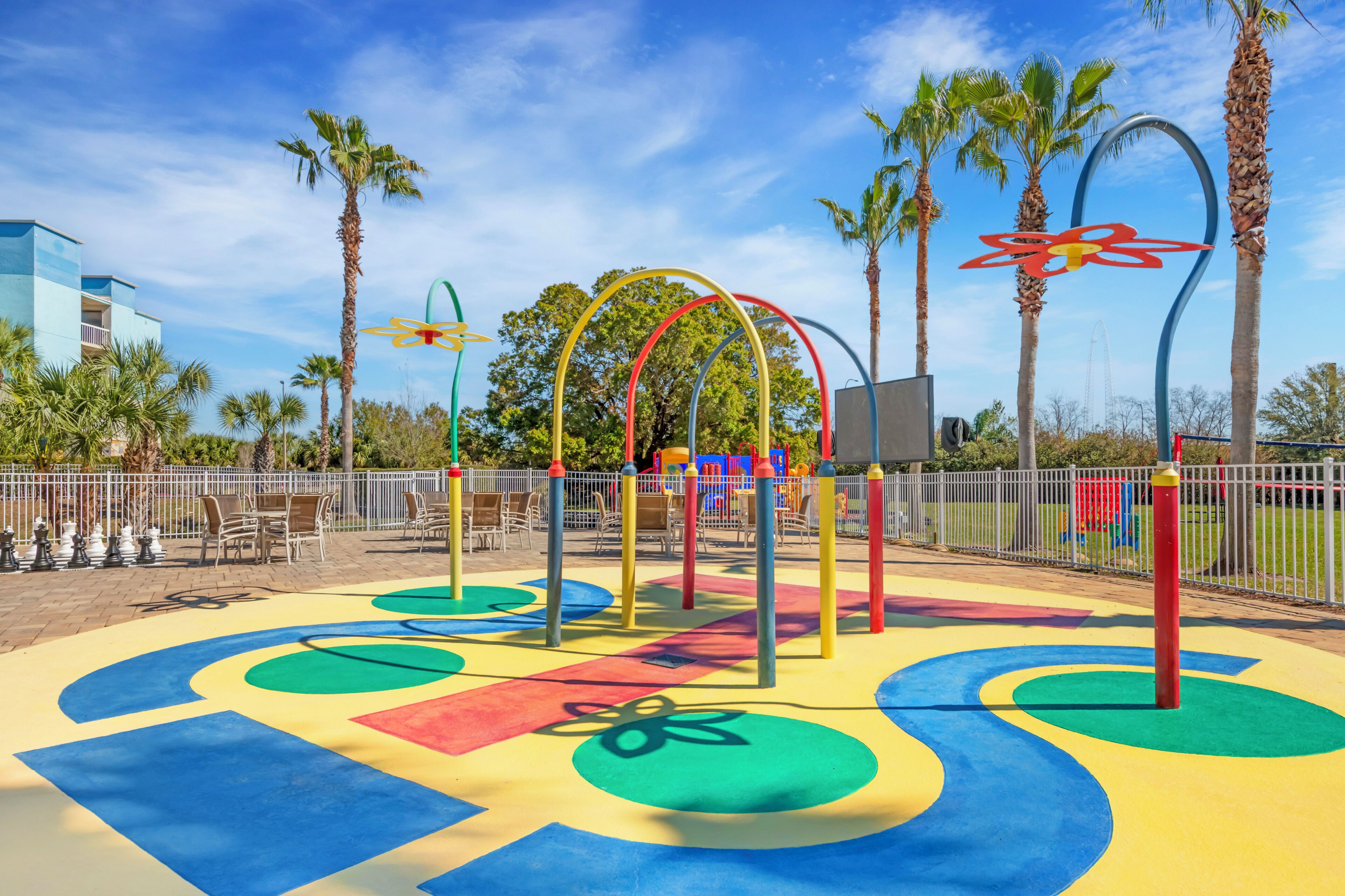 A playground with colorful play structures and palm trees.
