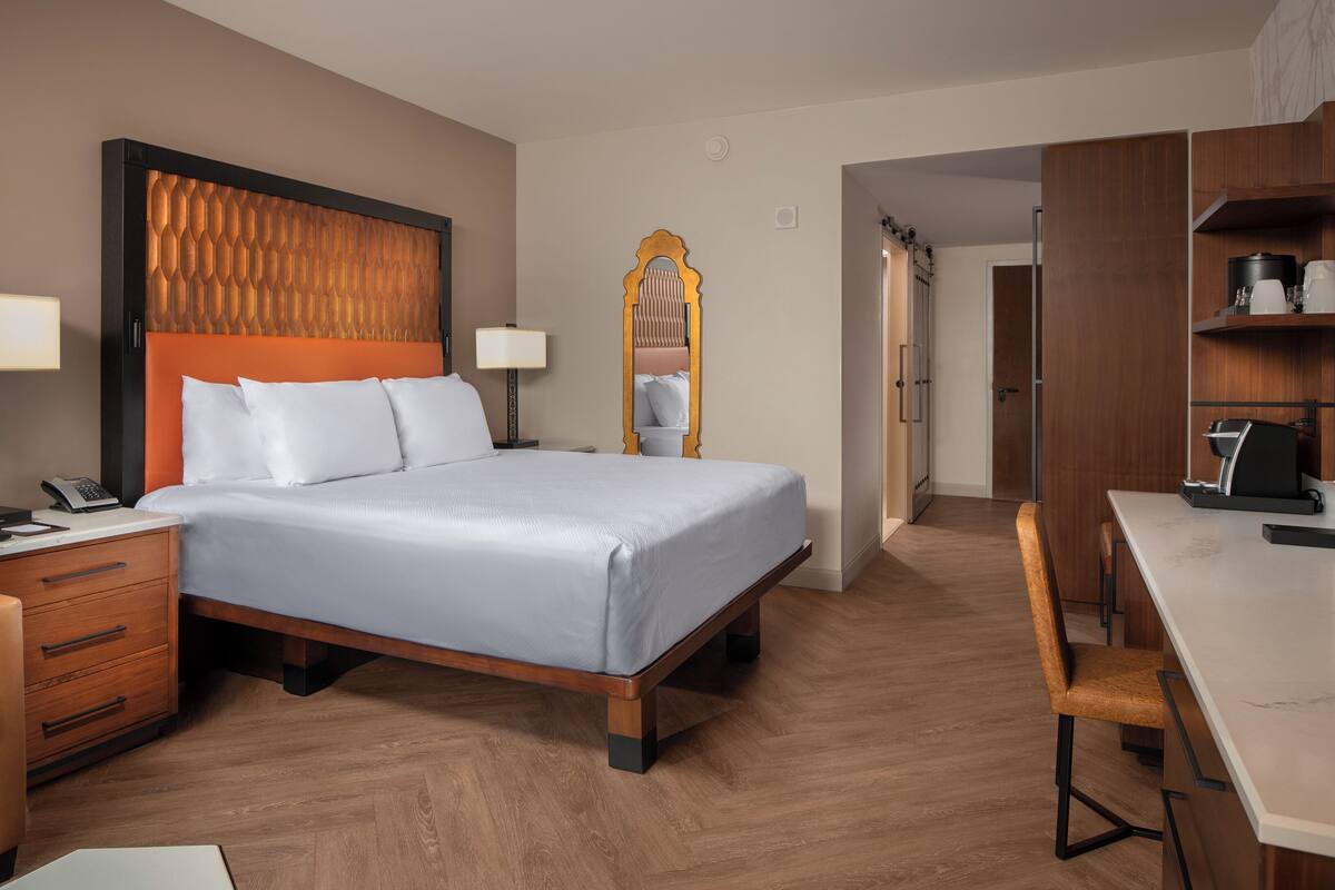 Een hotelkamer met een bed, nachtkastjes, een bureau en een kledingkast.