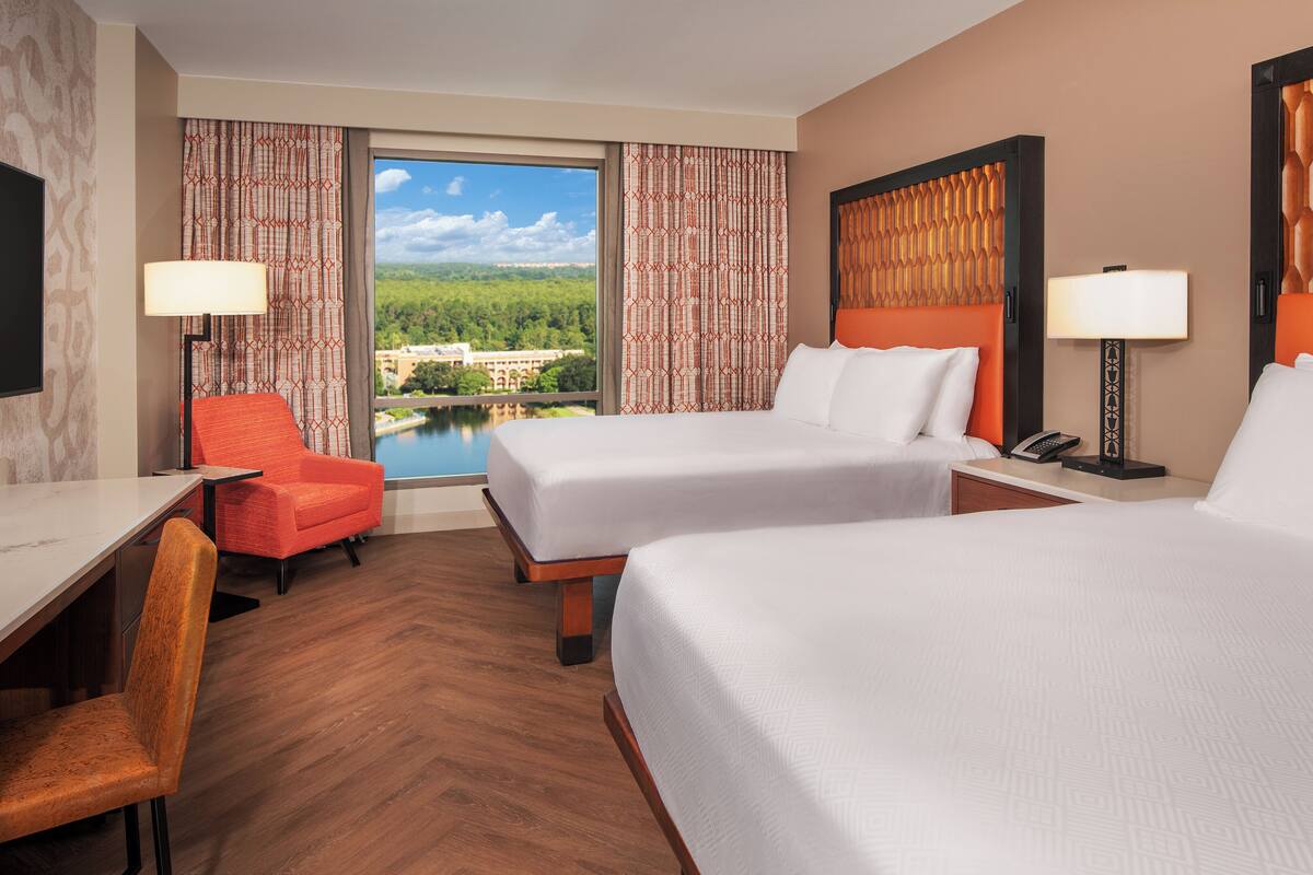 Een hotelkamer met twee bedden, een bureau, een stoel en een televisie.