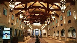 A spacious lobby with a high ceiling, ornate chandeliers, and a central plant. - Disney's Coronado Springs Resort (Lake Buena Vista)