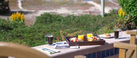 Une table dressée avec des aliments pour le petit-déjeuner, une boisson et une vue sur la mer et les bateaux.