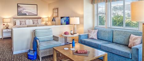 Una habitación de hotel acogedora con una cama, un sofá azul, una mesa de centro de madera y una silla de mimbre.