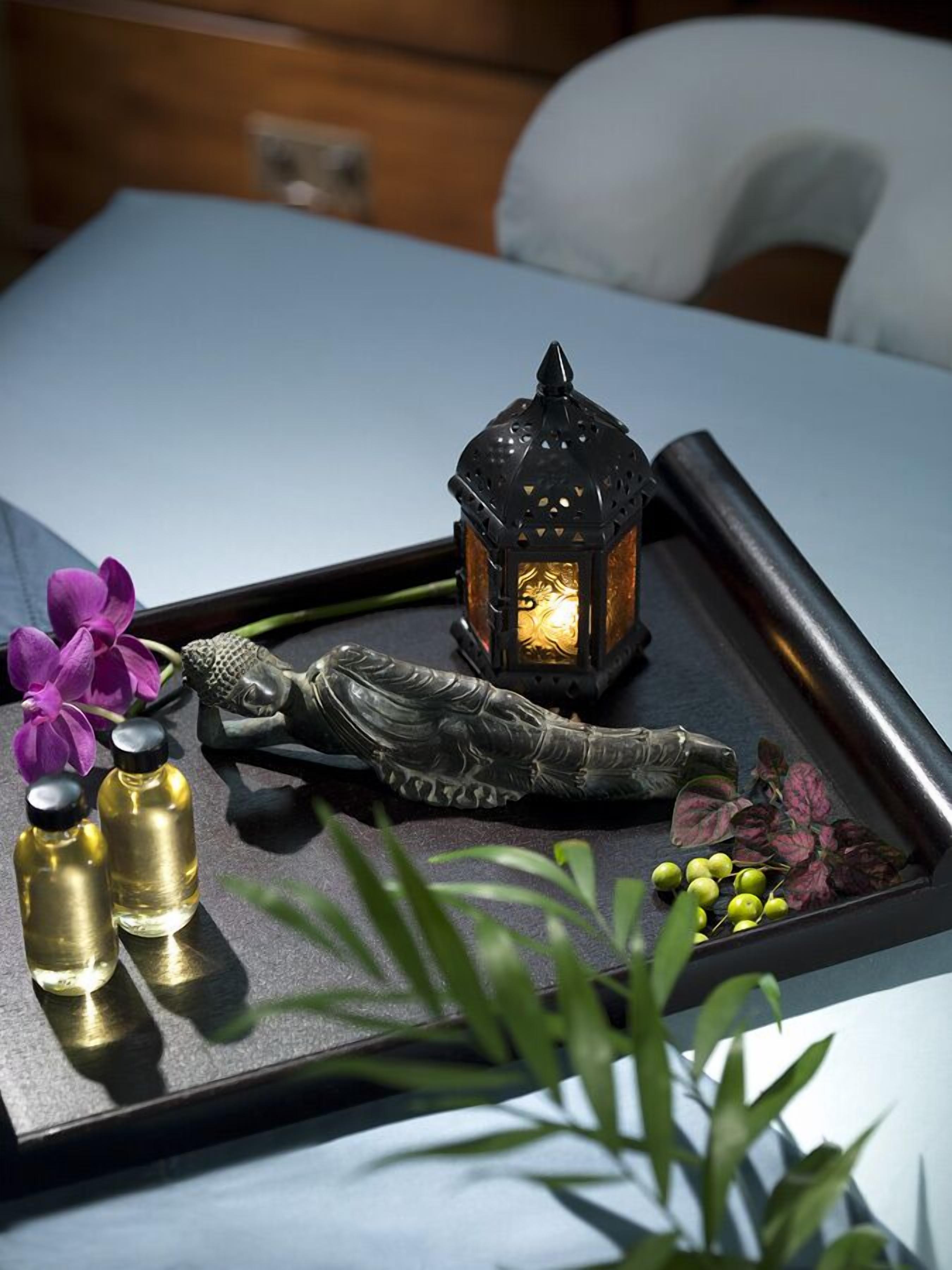 Een dienblad met een decoratieve lantaarn, een Boeddha-beeldje en flessen op een tafel.