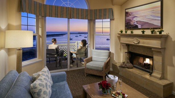 Een woonkamer met een groot raam met uitzicht op het strand, een open haard en een bank.