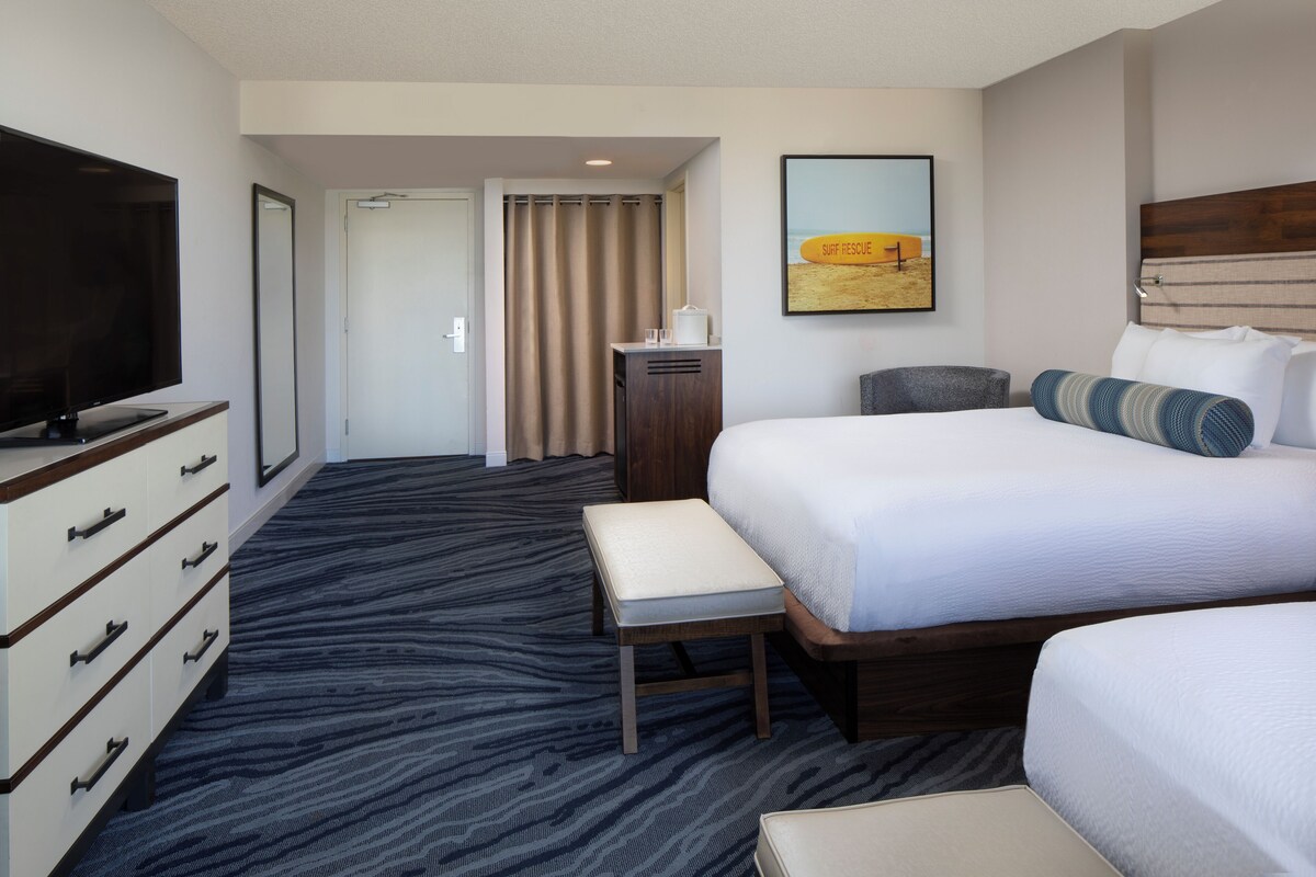 A hotel room with a large bed, a television, a desk, and a bathroom door.