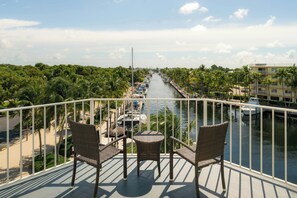 A balcony with wicker chairs and a small table overlooking a marina with boats and palm trees. - Courtyard by Marriott Key Largo (Key Largo)