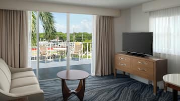 A hotel room with a balcony, a TV, a sofa, and a small table.