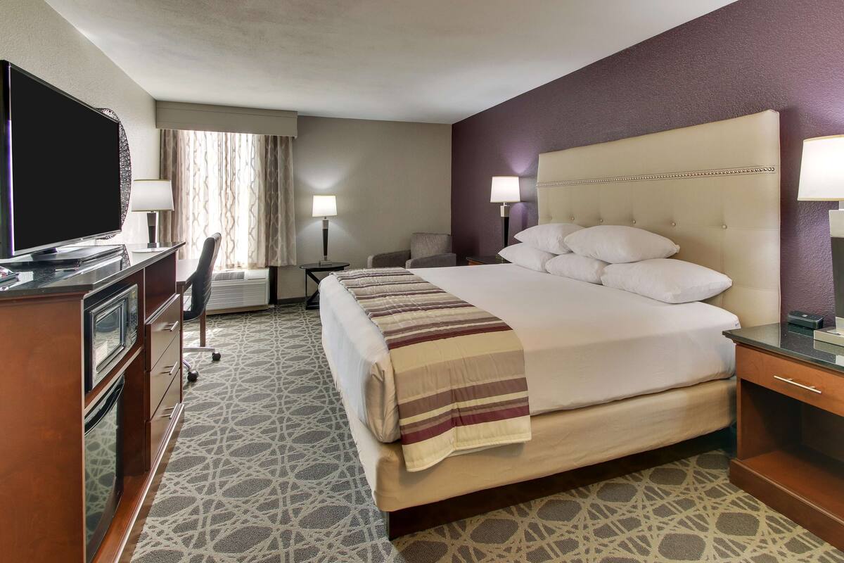 A hotel room with a large bed, a television, a desk, and a chair.