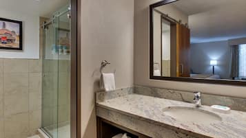 A bathroom with a glass shower enclosure, a marble sink, and a large mirror.