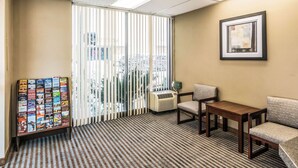A hotel room with a check-in counter, a vending machine, a small table, two chairs, and a large window with blinds. - Rodeway Inn Regalodge (Glendale)