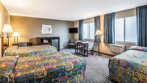 A hotel room with two beds, a desk, a chair, a TV, and a window with curtains. - Rodeway Inn Regalodge (Glendale)