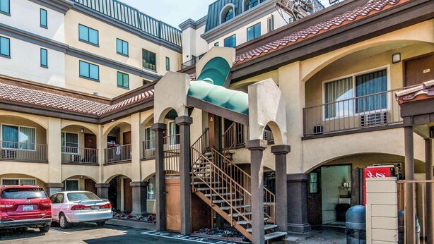 A multi-story hotel with a central spiral staircase, balconies, and a parking area with cars. - Rodeway Inn Regalodge (Glendale)
